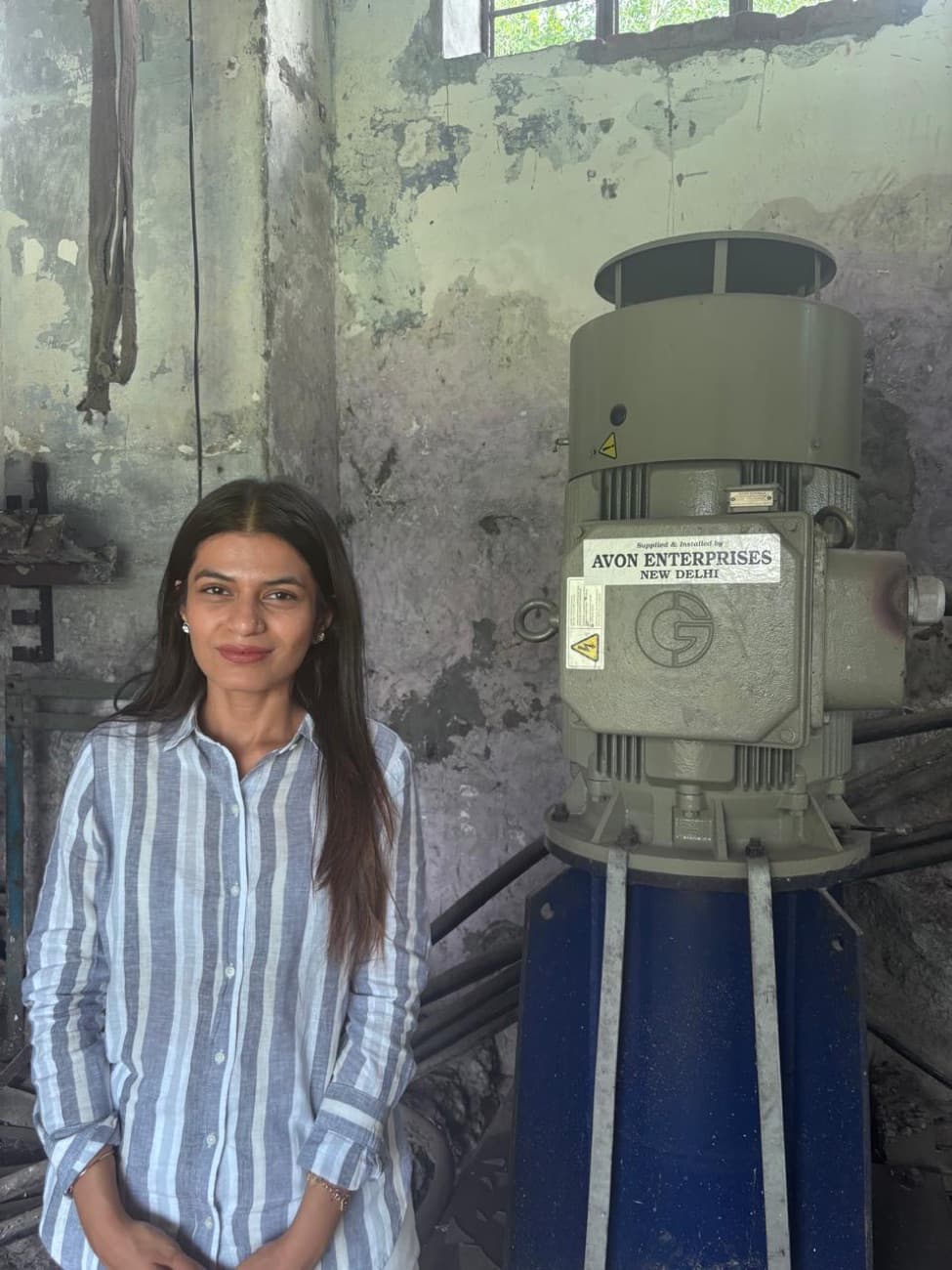 Disha Kapoor beside an Avon Enterprises pump motor during a facility inspection
